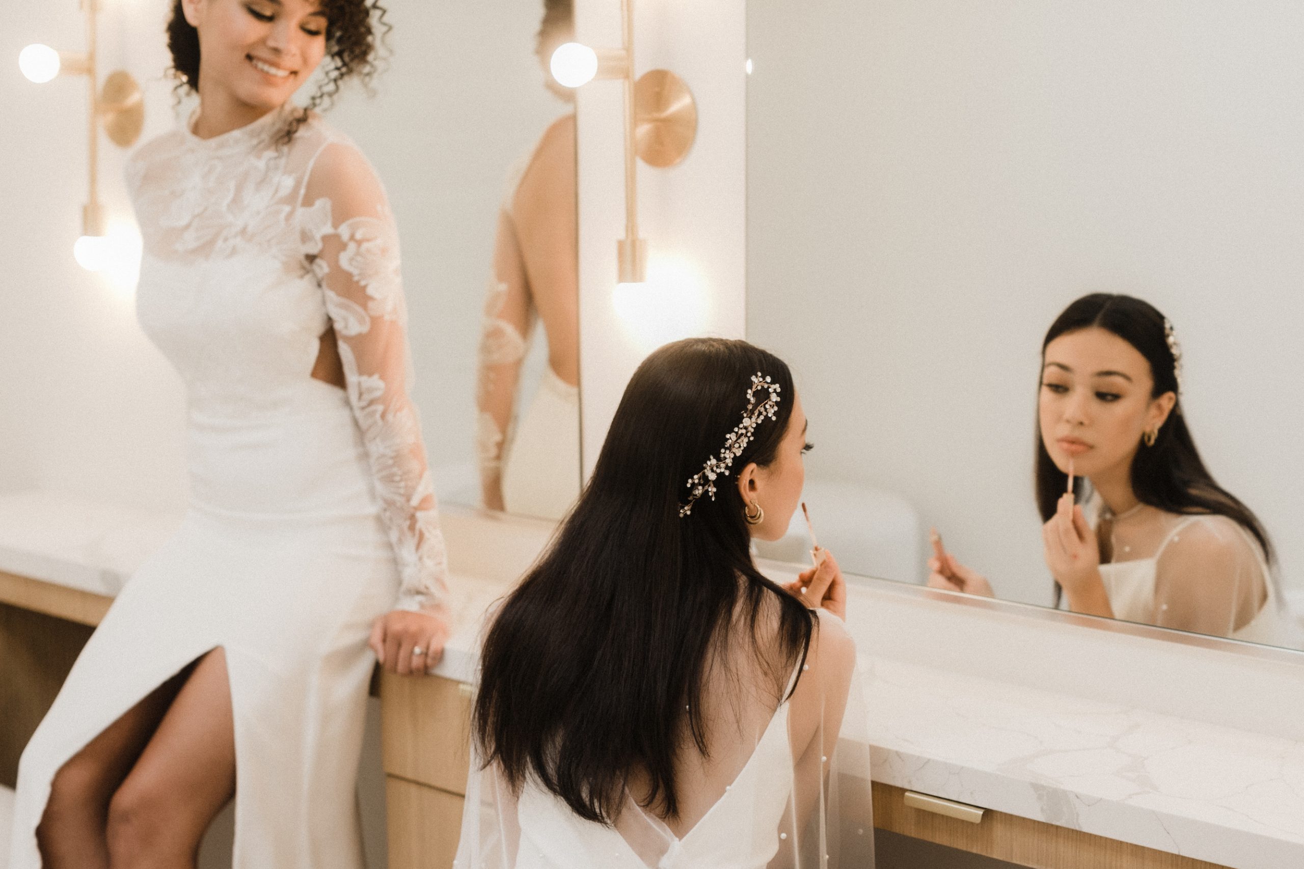 Two brides looking in the mirror applying makeup