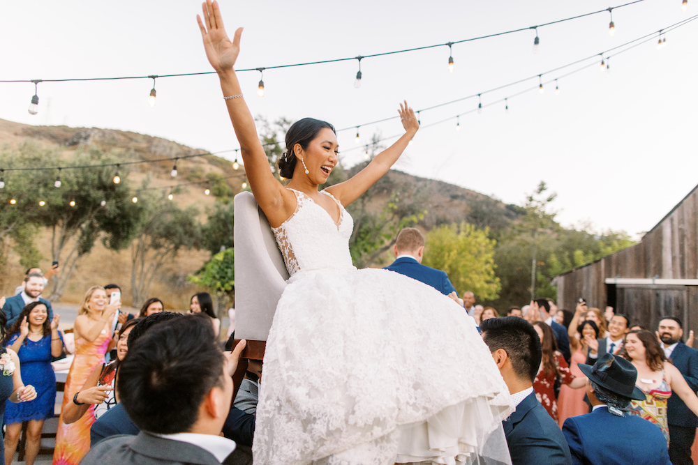 Bride sitting on a chair being lifted up