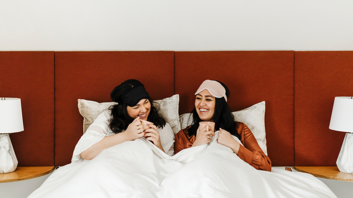two ladies in bed drinking coffee in pajamas